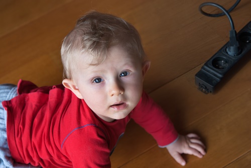 Little baby playing with electrical extension on floor at home