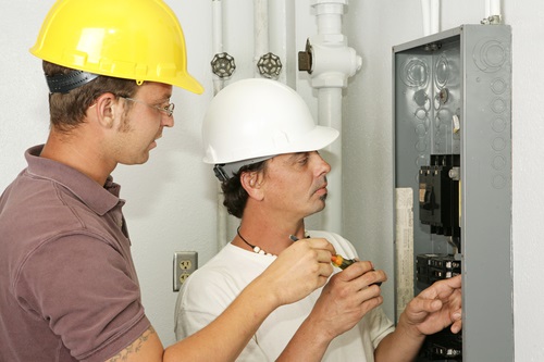 Electricians wiring an electrical breaker panel. Models are professional electricians - all work depicted is being performed according to industry codes and safety standards.