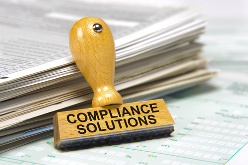 compliance solutions marked on rubber stamp